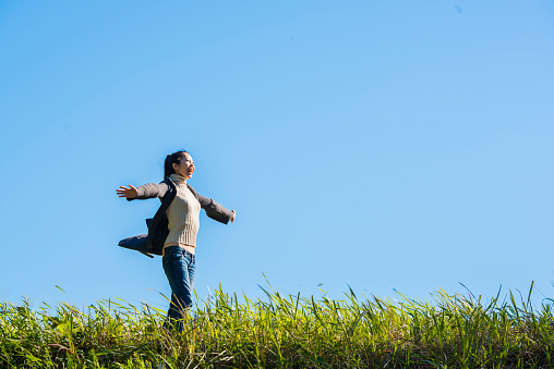 A Japanese woman looks up on the sky with a meadow