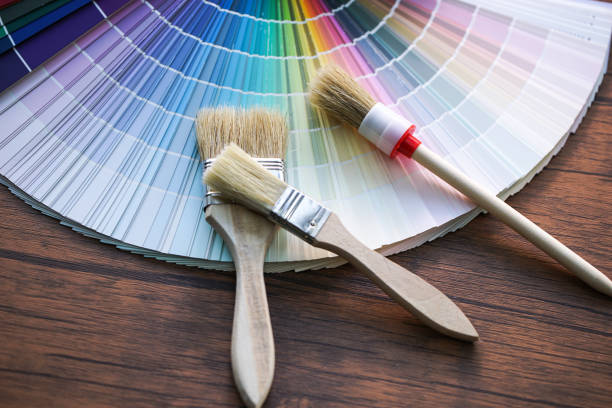 istock Painter and decorator work table with house project, color swatches, painting roller and paint brushes 953712842