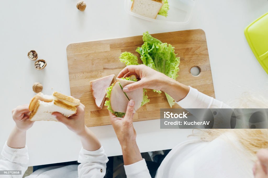 Mother with daughter eating sandwiches at home in the kitchen, top view Sandwich Stock Photo