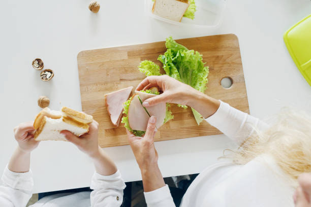 Mother with daughter eating sandwiches at home in the kitchen, top view Mother with daughter eating sandwiches at home in the kitchen, top view making a sandwich stock pictures, royalty-free photos & images