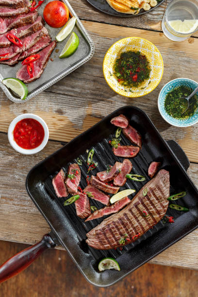 istock Beef meat cooked on the grill on wooden table with different sauces. Top view dinner table 953713210