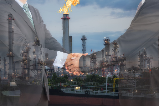 Businessmen handshaking in front of oil refinery plant. Agreement, Collaboration and  for oil and gas business concept.