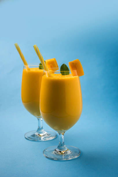 Mango Lassi or smoothie in big glass with mint leaf. Side angle  Isolated over colourful background. Selective focus
