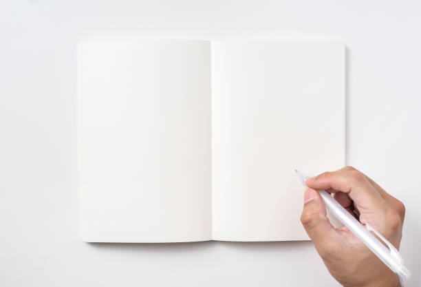 istock Top view of notebook blank page and man's hand holding ballpoint pen 953732672
