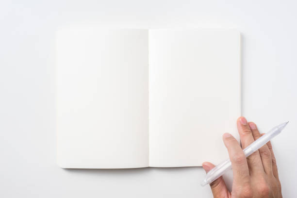 istock Top view of notebook blank page and man's hand holding ballpoint pen 953732910