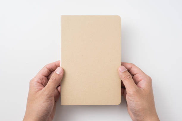 istock Top view of man's hand holding hardcover kraft notebook 953732966