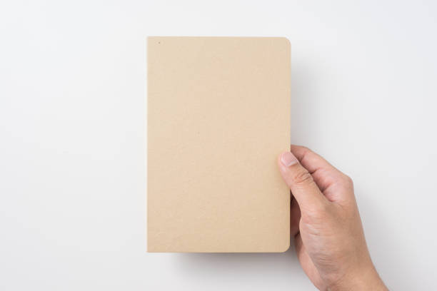 istock Top view of man's hand holding hardcover kraft notebook 953733028