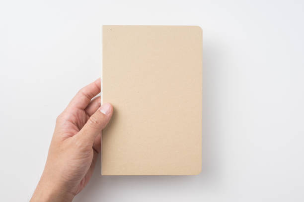 istock Top view of man's hand holding hardcover kraft notebook 953733122