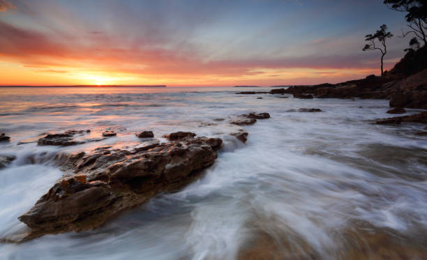 Sunrise Jervis Bay Australia Beautifuol sunrise over the bay as the ocean ebbs and flows gently over rocks at the shore edge shoalhaven stock pictures, royalty-free photos & images