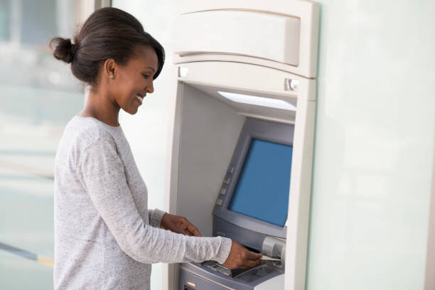 Customer cash withdrawals from an ATM machine. Bank customer woman inserting credit / debit card into an ATM, using the machine to withdraw cash money and for other financial services. exchange teller stock pictures, royalty-free photos & images