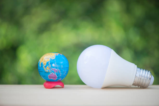 istock LED bulb and globe model with green nature background for saving energy concept 953742956