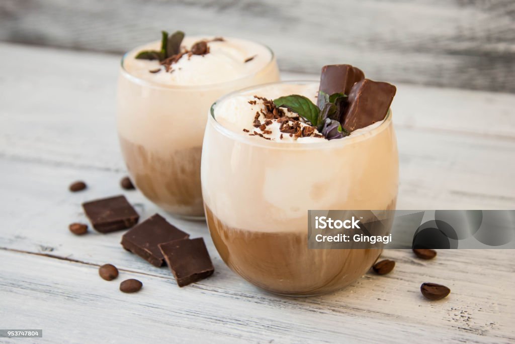 Iced Mocha Coffee with Whip Cream, Summer Drinking times. Coffee Beans. rustic textured Wooden Background. Mint Leaves Iced Mocha Coffee with Whip Cream, Summer Drinking times. Coffee Beans. rustic textured Wooden Background. Mocha Stock Photo