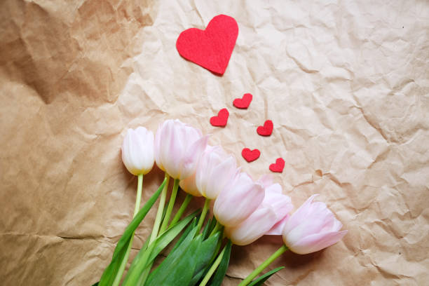 bouquet de tulipes roses et de la forme papier coeur rouge sur fond marron de papier froissé, bonne fête. - botany bright brown heart shape photos et images de collection