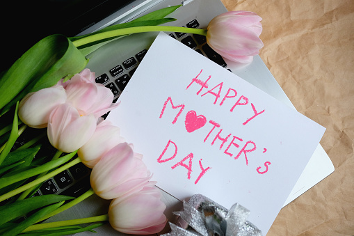 Bouquet of pink tulips and gift card on laptop, Happy mother's day.