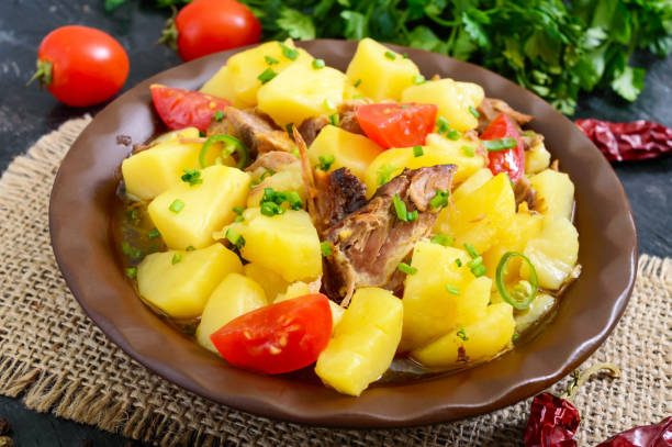 istock Stewed potatoes with meat in a ceramic bowl on a wooden table. 953764346