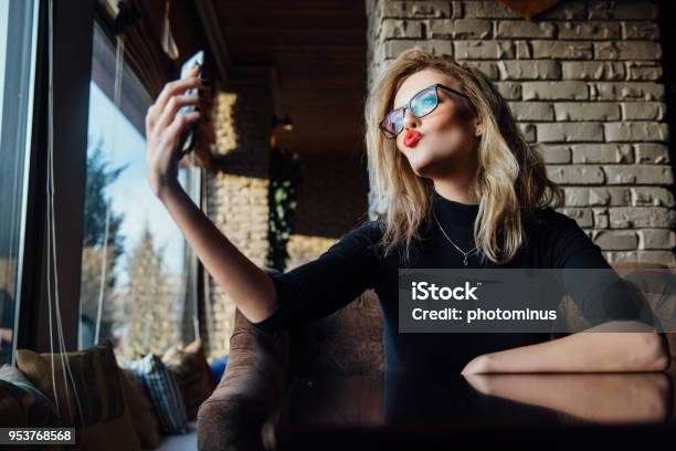 Young Beautiful Blonde Woman Taking A Selfie In Coffee Shop Hipster Red Lips Glasses Stock Photo - Download Image Now