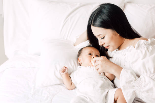istock Mother feeding baby from milk bottle on bed at hoe 953772584