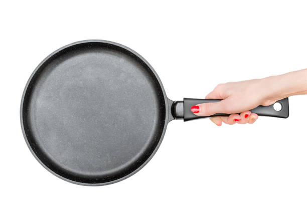 Female's hand holds frying pan. Isolated on white. Top view. stock photo