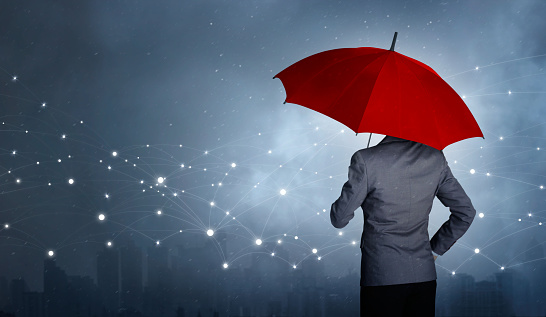 Businessman standing while holding and red umbrella over the networking connection and storm in city huge rain background. Business crisis and business leader concept, being different concepts