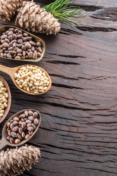 istock Pine nuts in the spoon and pine nut cone on the wooden table. 953784654
