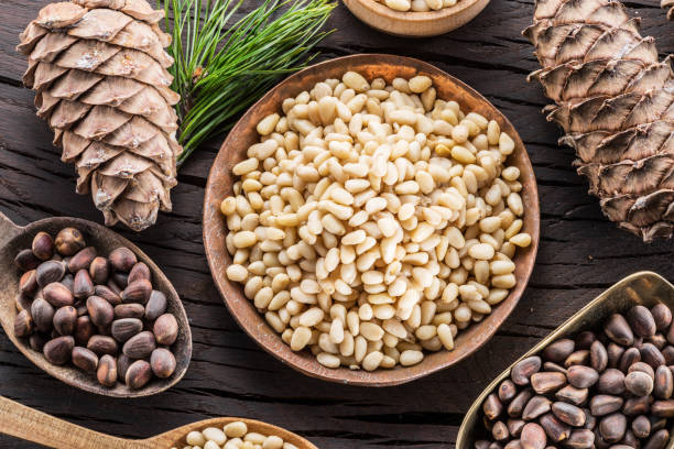 istock Pine nuts in the bowl and pine nut cones on the wooden table. 953786784