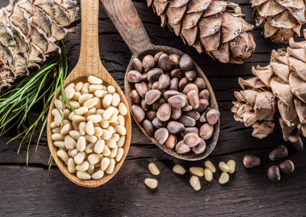 istock Pine nuts in the spoon and pine nut cone on the wooden table. 953786790