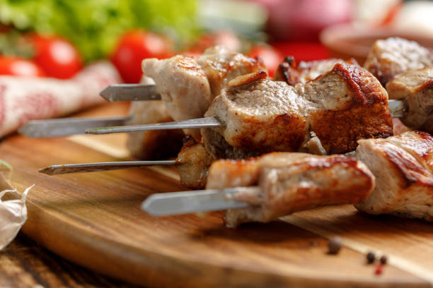istock Juicy kebabs of pork lined on a decorative board. Meat cooked on open fire and fresh vegetables. 953787496