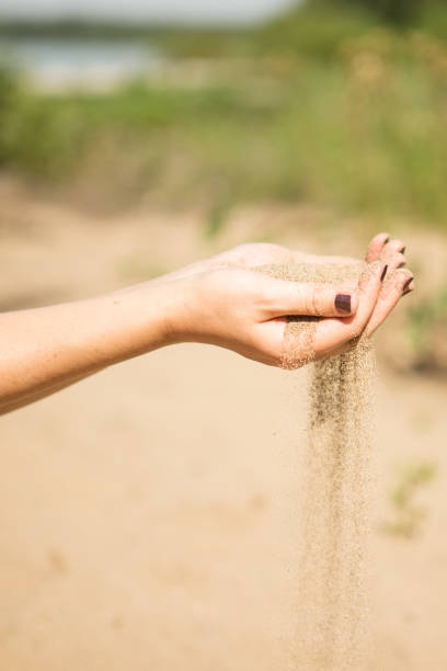 istock sand running through hands of woman 953799940