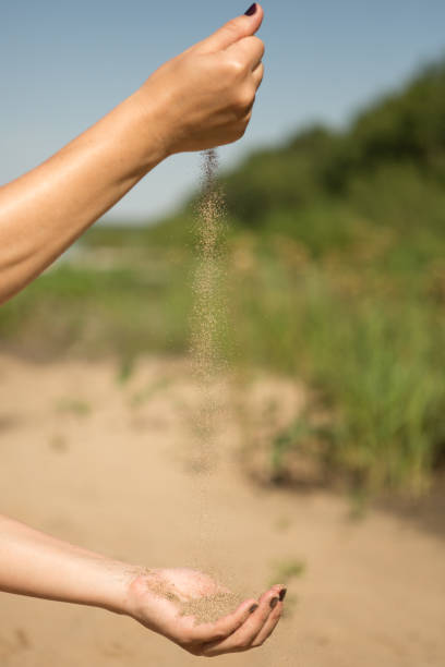 istock sand running through hands of woman 953799980