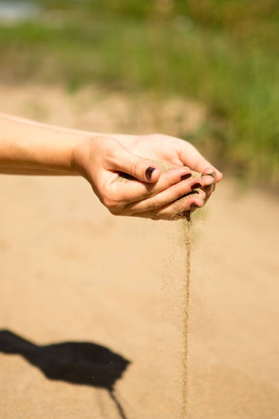 istock sand running through hands of woman 953800078