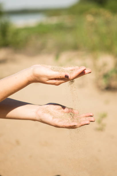 istock sand running through hands of woman 953800090