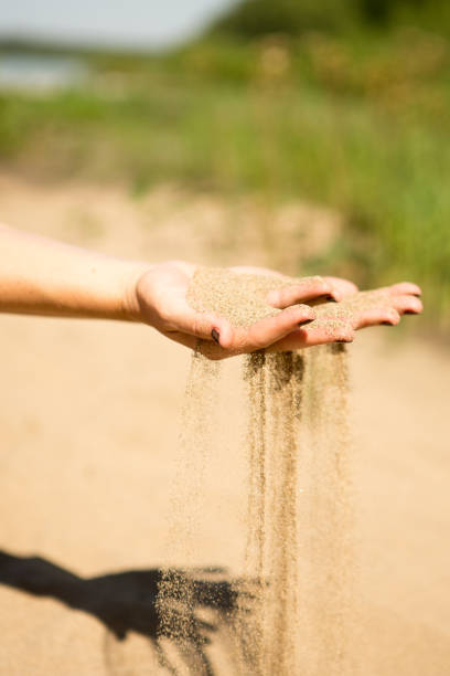 istock sand running through hands of woman 953800236