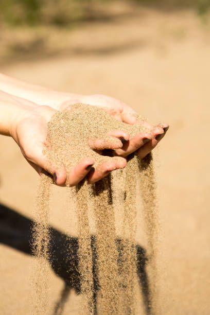 istock sand running through hands of woman 953800314