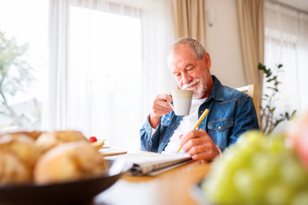 istock Senior man eating breakfast and doing crosswords at home. 953800768
