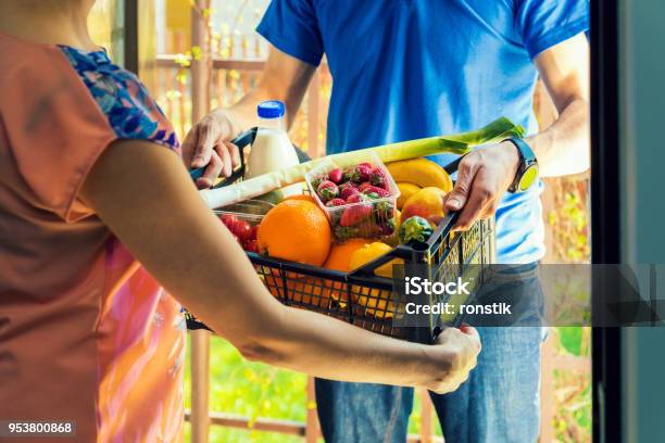Woman Accepting Groceries Box From Delivery Man At Home Stock Photo - Download Image Now