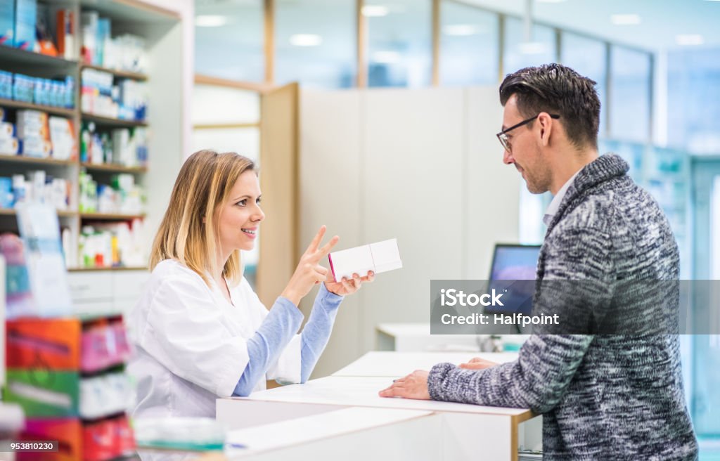 Female pharmacist serving a male customer. Female friendly pharmacist serving a male customer. Pharmacy Stock Photo