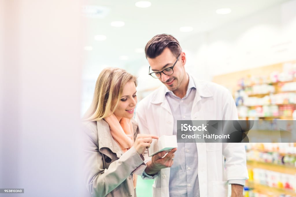 Farmacista maschio al servizio di un cliente femminile. - Foto stock royalty-free di Farmacista