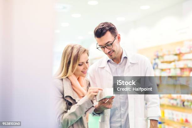 Farmacista Maschio Al Servizio Di Un Cliente Femminile - Fotografie stock e altre immagini di Farmacista