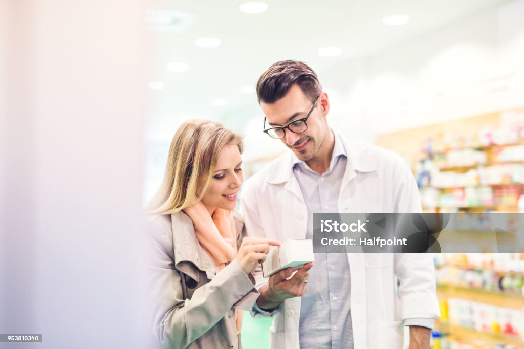 Male pharmacist serving a female customer. Handsome male friendly pharmacist serving a female customer. Pharmacist Stock Photo