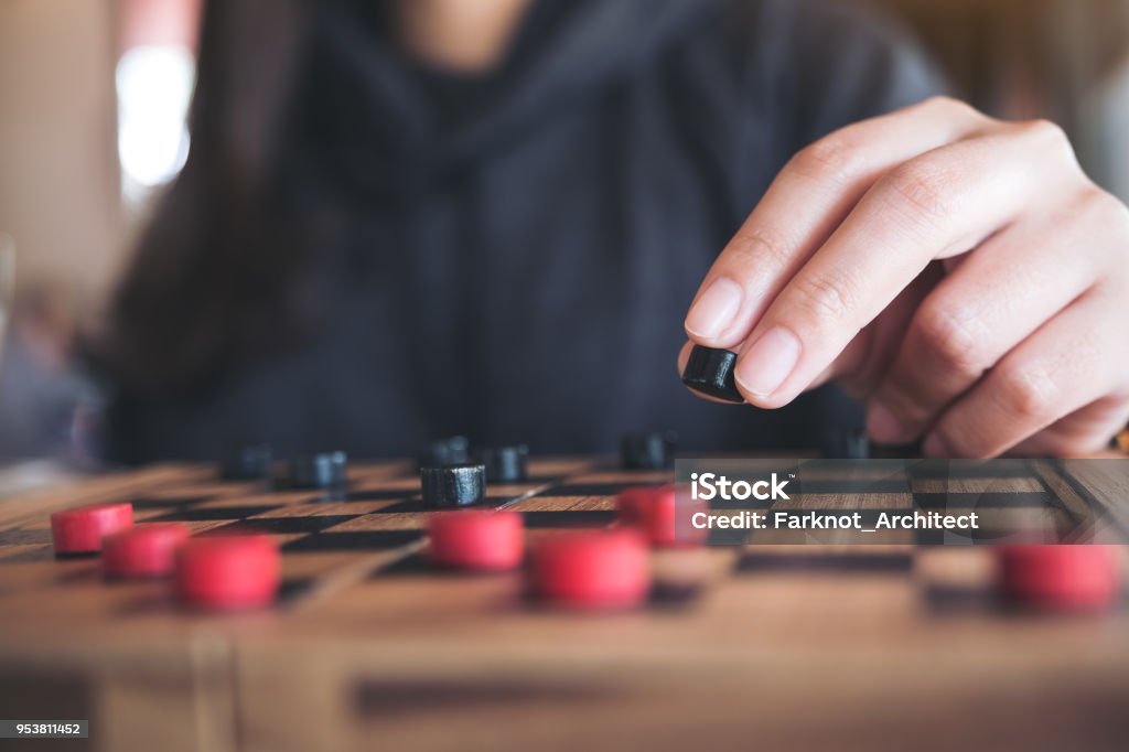 Closeup image of people playing and moving checkers in a chessboard Checkers Stock Photo