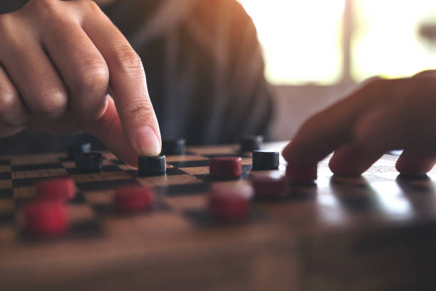 istock Closeup image of people playing and moving checkers in a chessboard 953811618