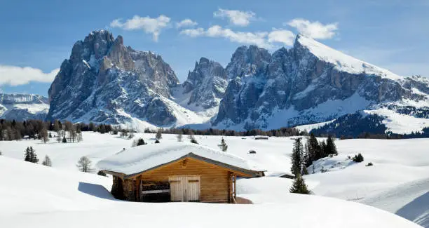 Langkofel mountains and wooden stable in snow covered landscape. 
Location: View on Langkofel from Seiser Alm, Dolomites, Alto Adige, Italy.