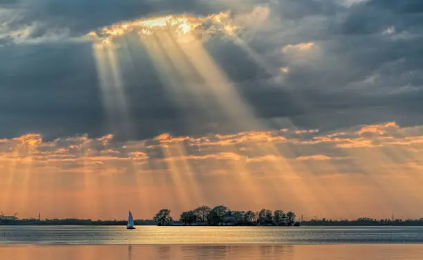 Photo of Sunbeams through cloudscape on lake.