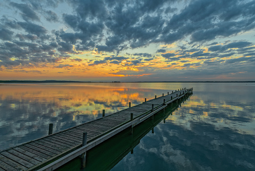 Jetty and lake with majestic reflection of cloudscape at dusk. Location: Lake Steinhuder Meer, Lower Saxony, Germany.