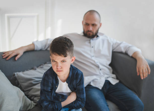 istock A sad and resentful boy and an angry father in the background 953823626