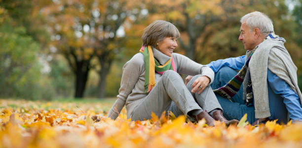 istock Active senior couple sitting on autumn colored leaves in park 953824330