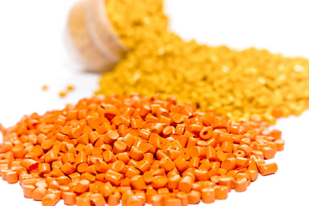 istock Plastic resin. Plastic pellets. Orange green and pink Polypropylene granules scattered on the lab table . Polymeric dye. 953828474