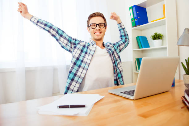 istock Handsome smiling man in glasses stretching hands after working day 953830428