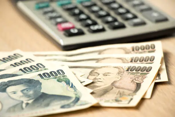 Japanese yen banknote and calculator on wood table background