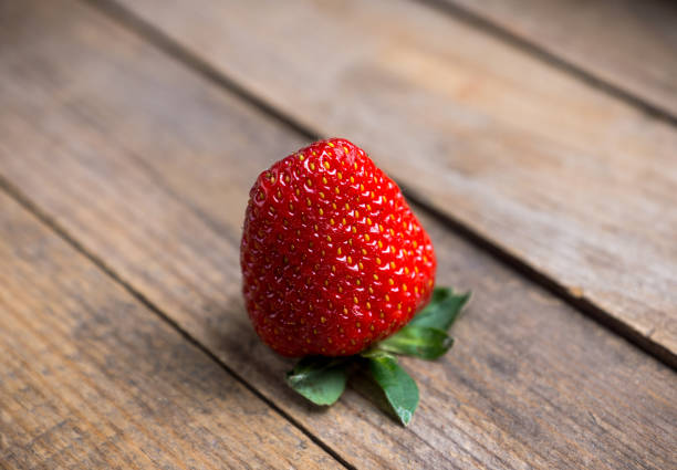 Red ripe strawberry on the rustic background. Selective focus.